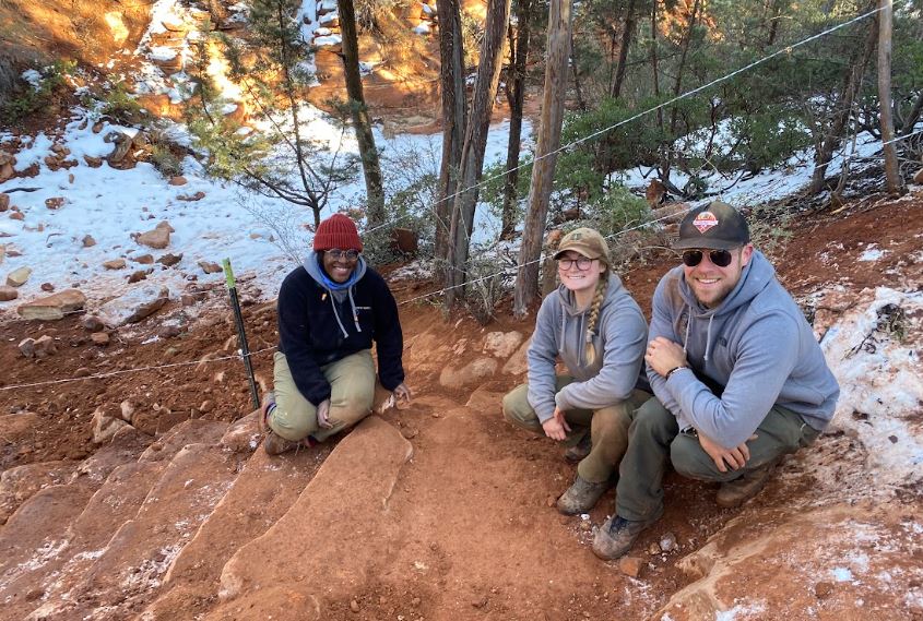 3 workers smiling on rock staircase