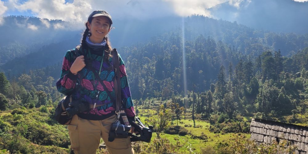 Annamaria Savrino, photographer, standing in a jungle with a camera.