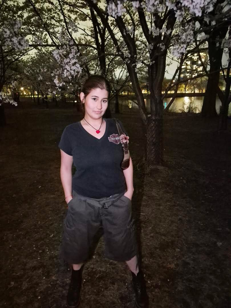 A picture of Genevieve and behind is cherry blossom trees.