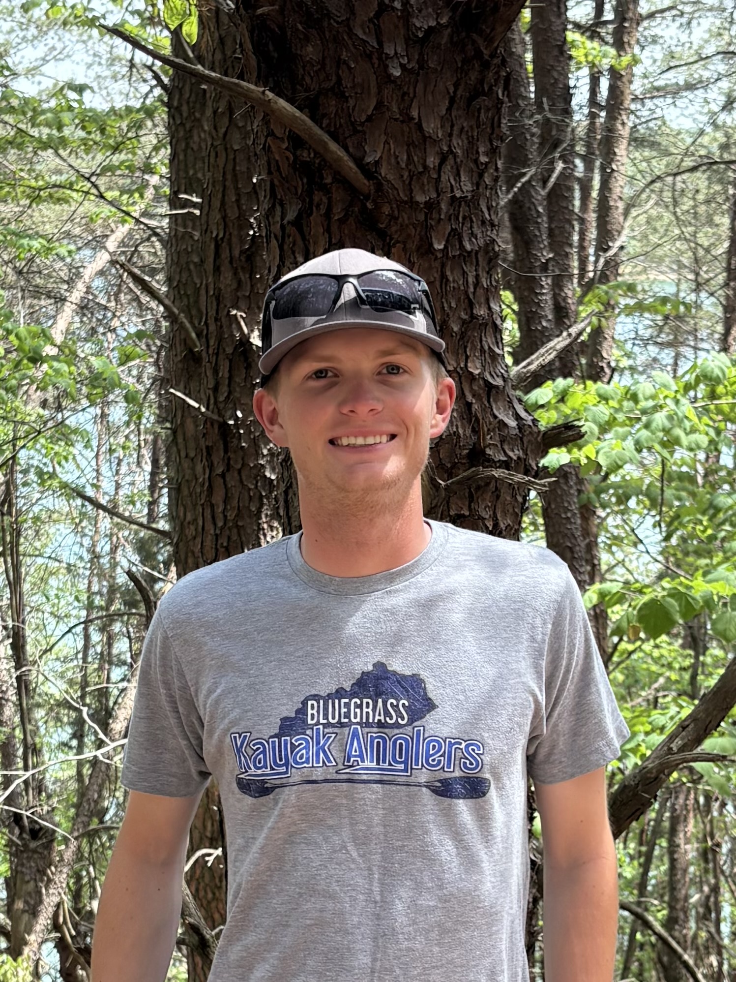 Photo of Nate standing in front of a pine tree.