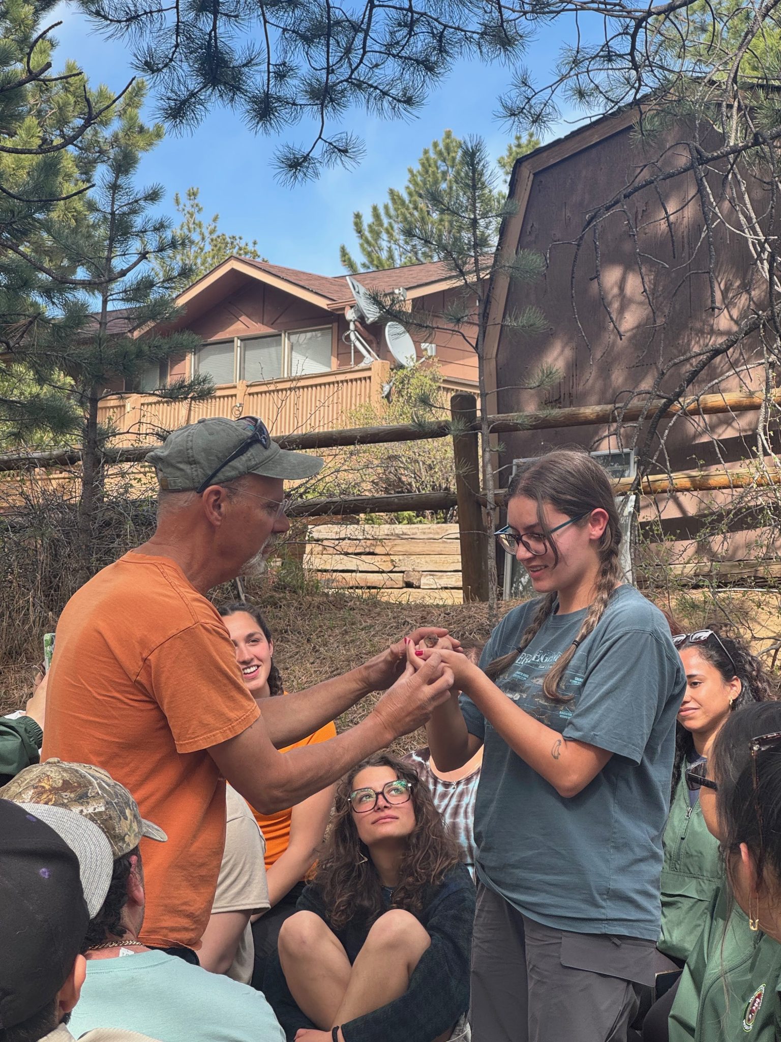 Dhara is being handed a bird during a bird banding demonstration. Other interns can be seen in the background watching.