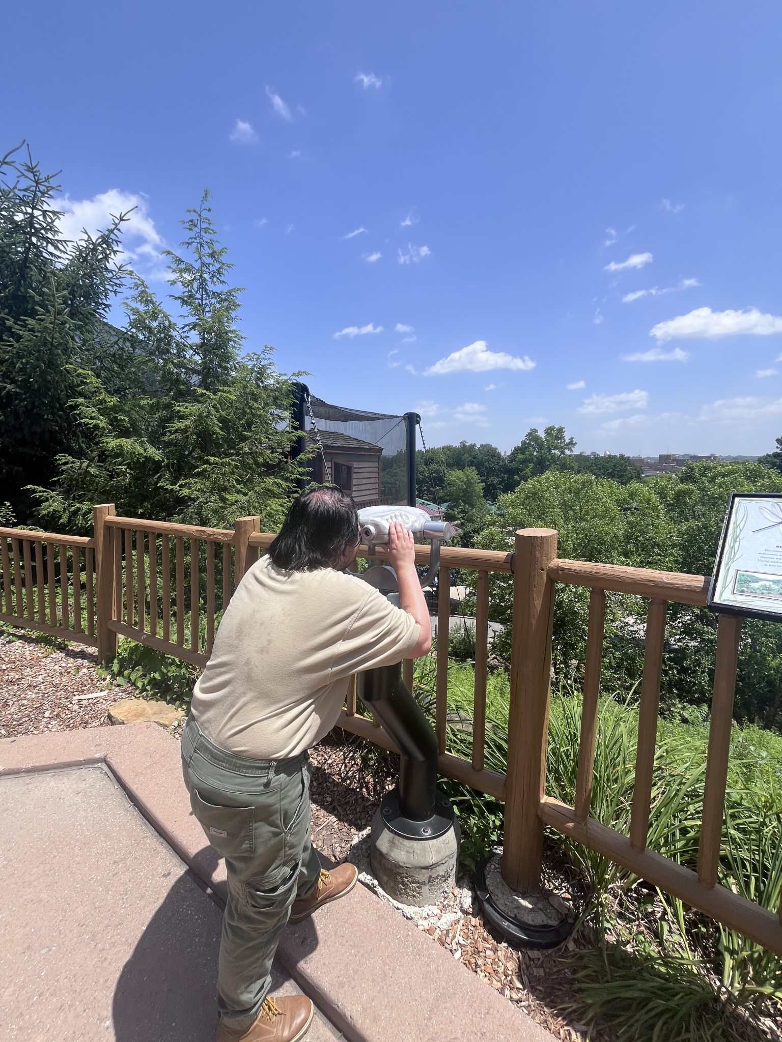 Person with black hair and tan shirt looks through a telescope.