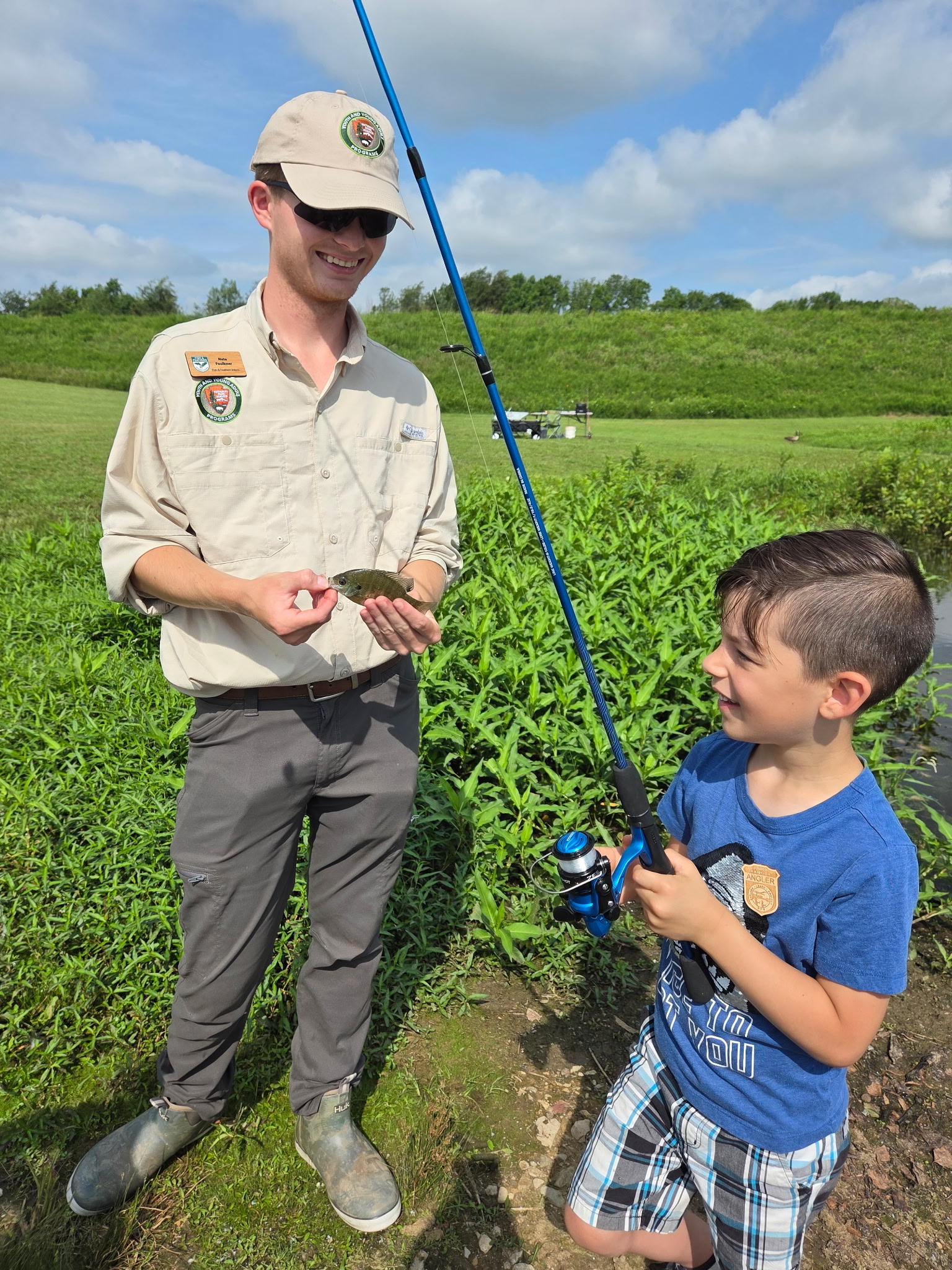 Nate holding a fish next to a kid who caught it