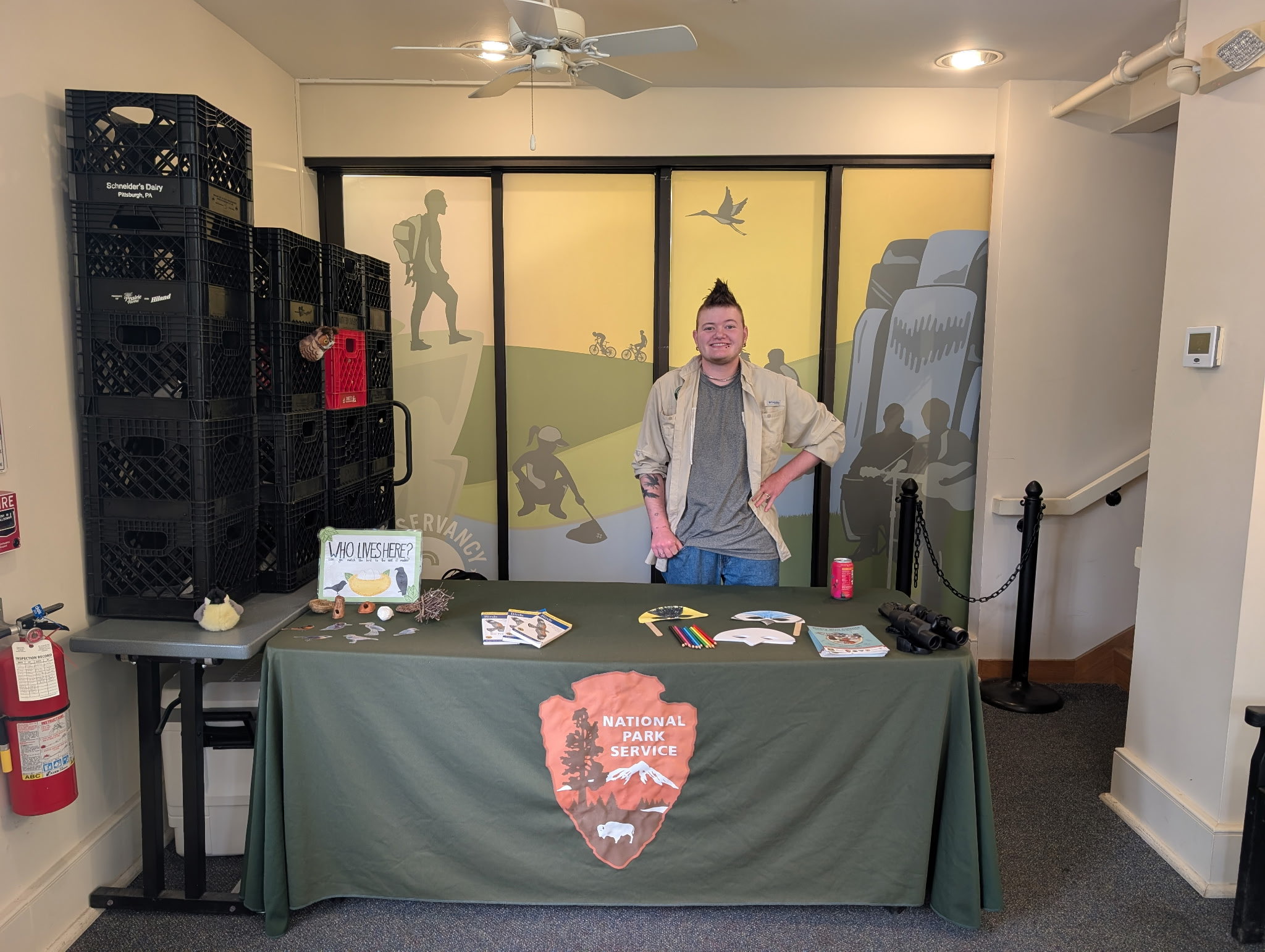Zack standing at a table with various bird-related activities. There is a nest matching game and bird masks with colored pencils available.